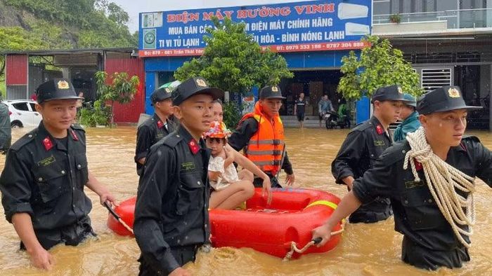 Lực lượng chức năng hỗ trợ người dân di chuyển đến nơi an toàn sau trận mưa lớn gây ngập úng tại phường Lào Cai ngày 3/8.
