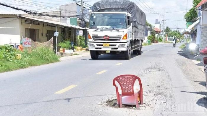 Người dân dùng ghế che chắn ổ gà để người tham gia giao thông tránh né vị trí hư hỏng trên tuyến đường.