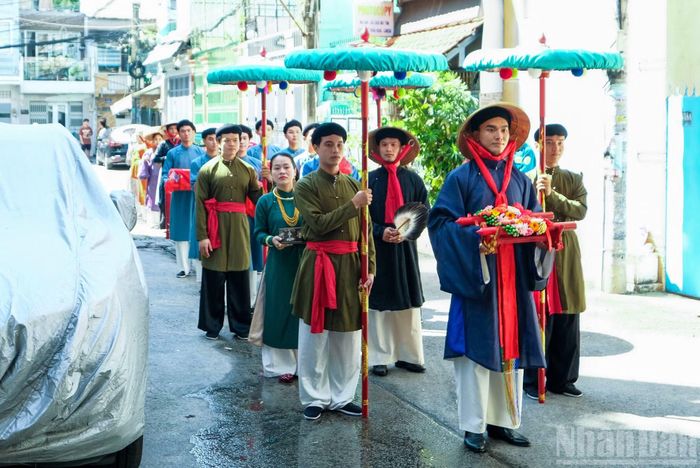 Đại diện nhà trai chỉnh tề trong trang phục truyền thống, mang các mâm quả gồm trầu cau, trà, rượu và lễ vật sang nhà gái.