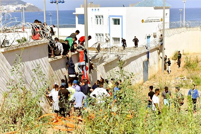 Người di cư trèo qua hàng rào biên giới để vào vùng lãnh thổ Ceuta của Tây Ban Nha từ thành phố Fnideq, Morocco. ẢNH: THX