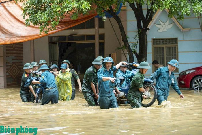 Cán bộ, chiến sĩ các đơn vị hỗ trợ người dân bị ảnh hưởng bởi mưa lũ di dời tài sản ra khỏi khu vực nguy hiểm. Ảnh: Biên Cương