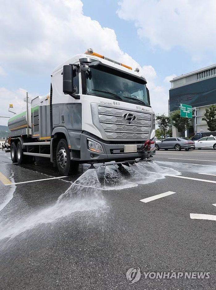 Phun nước xuống đường để hạ nhiệt. (Ảnh: Yonhap)