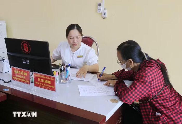 Người dân đến làm thủ tục hành chính được cán bộ xã Việt Hồng hướng dẫn tận tình. (Ảnh: Đinh Thùy/TTXVN)