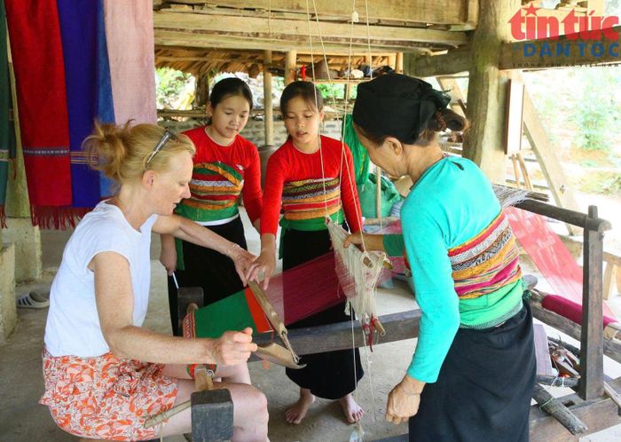 Du khách nước ngoài tập làm nghề dệt thổ cẩm.