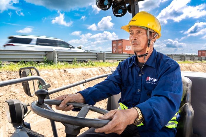 Công nhân vận hành xe lu, khẩn trương hoàn thiện nền đường tại dự án mở rộng cao tốc.