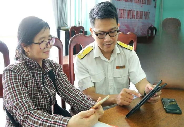 Công chức Thuế cơ sở 1 hỗ trợ người nộp thuế cài đặt và sử dụng ứng dụng thuế điện tử trên điện thoại thông minh. Ảnh: T.S