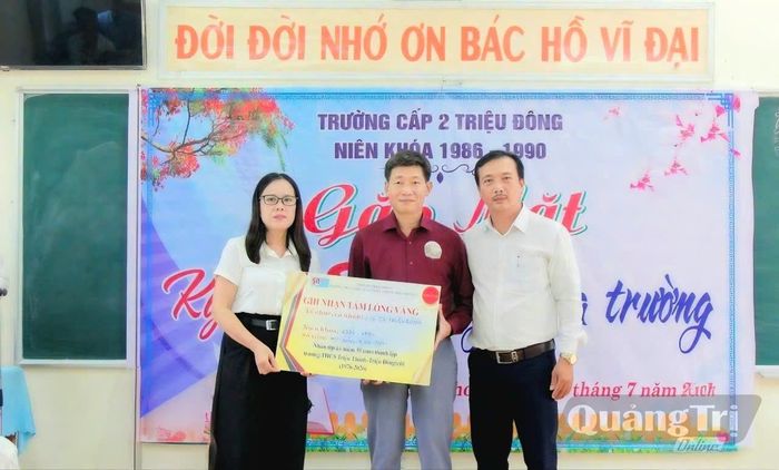 Lãnh đạo trường tiếp nhận quà của cựu học sinh tặng học bổng cho học sinh có hoàn cảnh khó khăn - Ảnh: N.T
