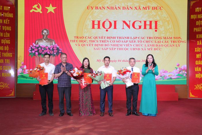 Phó Bí thư Thường trực Đảng ủy xã Mỹ Đức Nguyễn Thị Thúy Hòa và Chủ tịch UBND xã Mỹ Đức Nguyễn Quang Đường trao quyết định bổ nhiệm Ban Giám hiệu Trường Tiểu học Mỹ Đức A. Ảnh: Biên Phạm