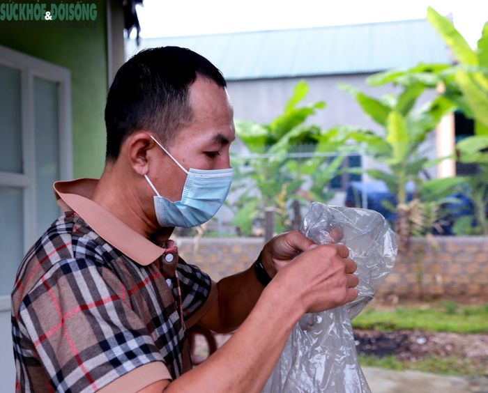 Lộc Văn Hai kiểm tra lại chiếc áo mưa đã rách trước khi lên đường đến các bản làng tìm người bệnh lao. ẢNH: Vũ Đồng