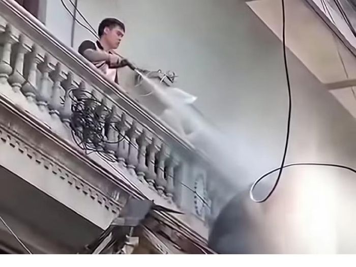 Nguyễn Duy Mạnh xịt nước vào người thợ đang tháo dỡ. Ảnh: Cắt từ clip