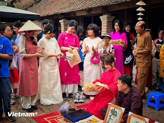 Du khách Hàn Quốc trải nghiệm với di sản tranh dân gian Đông Hồ của Việt Nam. (Ảnh: Mai Mai/Vietnam+)