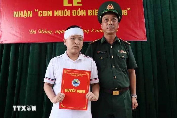 Chỉ huy Tiểu đoàn Huấn luyện-Cơ động, thuộc Ban chỉ huy Bộ đội biên phòng thành phố Đà Nẵng trao Quyết định nhận làm con nuôi cho cháu L.V.H.P. (Ảnh: Đoàn Hữu Trung/TTXVN)