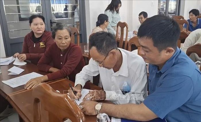Người dân ký xác nhận đồng ý phương án hỗ trợ thiệt hại do UBND phường Tân Thành công bố. Ảnh: TTXVN phát