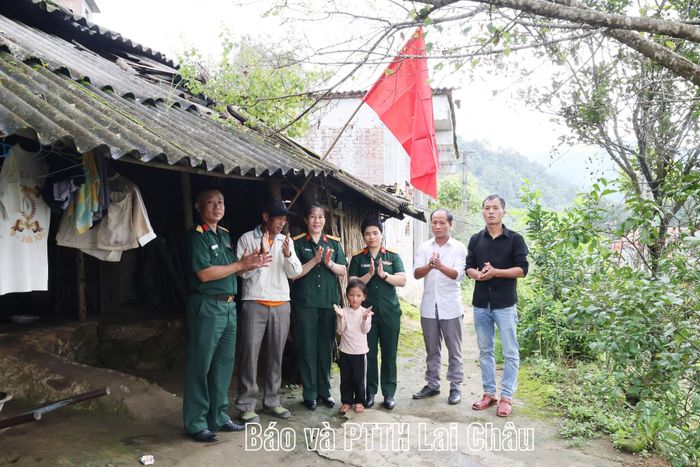 Đại diện Đoàn Kinh tế - Quốc phòng 356 trao cờ Tổ quốc và ảnh Bác Hồ cho nhân dân bản Tỷ Phùng và giúp nhân dân treo cờ Tổ quốc. 