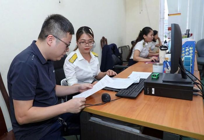Công chức Thuế hỗ trợ hộ kinh doanh làm sạch mã số thuế. Ảnh: Đức Thanh