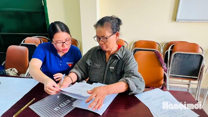 Chị Nguyễn Hiền Phương, đoàn viên Trường Tiểu học Phú Thượng, hỗ trợ người dân đối chiếu, cập nhật dữ liệu đất đai. Ảnh: Tuệ Lâm