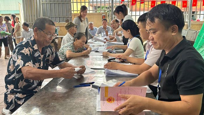 Người dân thôn Thụy Ứng bàn giao cho cán bộ xã Giấy chứng nhận quyền sử dụng đất trước khi nhận tiền chi trả, bồi thường GPMB dự án đầu tư xây dựng Khu đô thị thể thao Quốc tế Hà Nội. Ảnh: PV