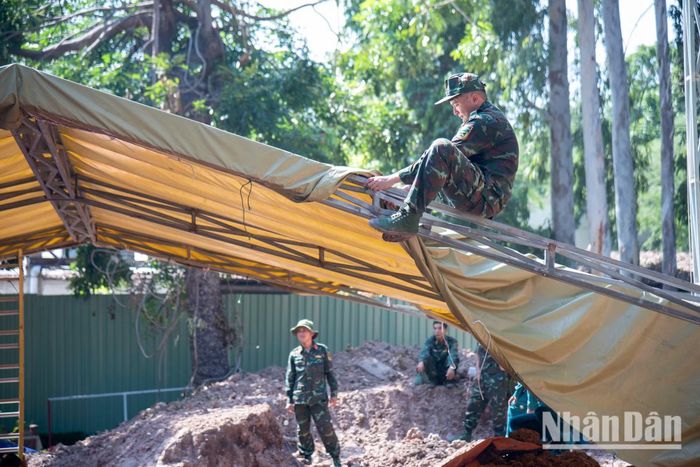 Để đối phó với mưa lớn trút xuống bất ngờ, các chiến sĩ phải che chắn kỹ lưỡng nhằm bảo vệ những khu vực nghi ngờ có hài cốt.