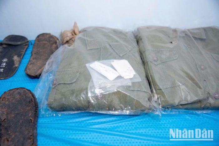 Dù đã nằm sâu dưới lòng đất hàng chục năm, những bộ quân phục tìm thấy cùng hài cốt liệt sĩ có những bộ vẫn giữ được hình dạng. Từng sợi vải đã hóa màu đất rừng vẫn âm thầm kể lại câu chuyện về những đêm hành quân băng rừng, lội suối, những ngày nắng Trường Sơn đổ lửa.