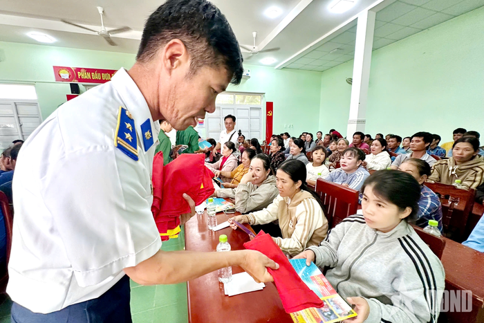  Cán bộ Vùng Cảnh sát biển 3 phát tờ rơi, tặng cờ Tổ quốc cho người dân. 
