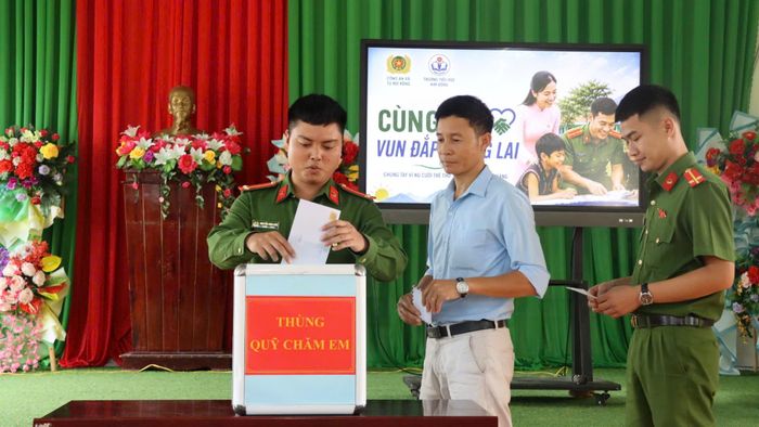 Các chiến sĩ công an cùng lãnh đạo trường tham gia ủng hộ Thùng quỹ chăm em. Ảnh: HỮU PHÚC
