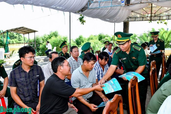 Cán bộ Đồn Biên phòng Trung Bình cấp phát tờ rơi tuyên truyền chống khai thác IUU cho các ngư dân tham dự lễ ra quân. Ảnh: Văn Long