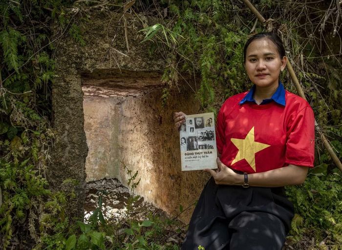 Em Phạm Thị Thanh Trúc với cuốn Nhật ký Đặng Thùy Trâm trước căn hầm nơi chị từng trú ẩn trên rừng. Ảnh: Lê Văn Chương