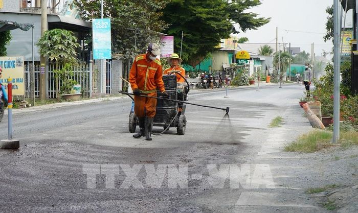 Công nhân tưới nhựa thấm bám, chuẩn bị thảm nhựa Quốc lộ 30, đoạn qua ấp Gò Da, xã Tân Hồng. Ảnh: Nhựt An - TTXVN