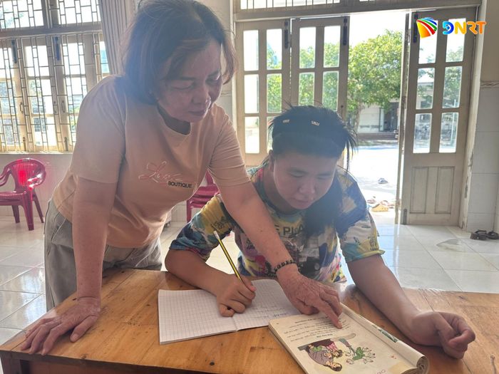Bà Tiềm hướng dẫn các em viết chữ. Ảnh: Hà Quang
