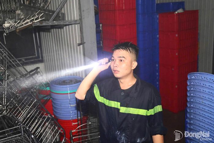 Một chiến sĩ cảnh sát phòng cháy, chữa cháy bám trụ hiện trường, nỗ lực tìm tài sản cho tiểu thương sau đám cháy. Ảnh: Công Nghĩa