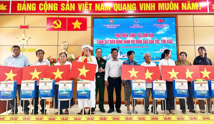 Đại diện Ban Chỉ huy Bộ đội Biên phòng tỉnh và lãnh đạo xã Phước Dinh trao tặng cờ Tổ quốc cho ngư dân.