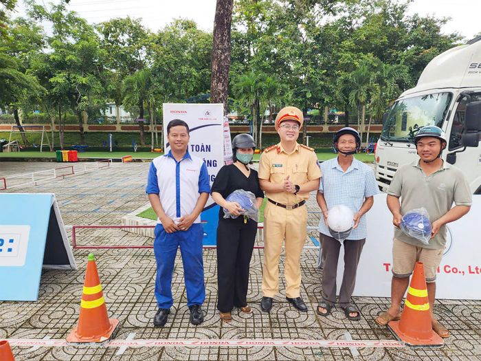 Lực lượng CSGT trao mũ bảo hiểm đạt chuẩn cho người dân sau buổi hướng dẫn kỹ năng. Ảnh Lê Tiến