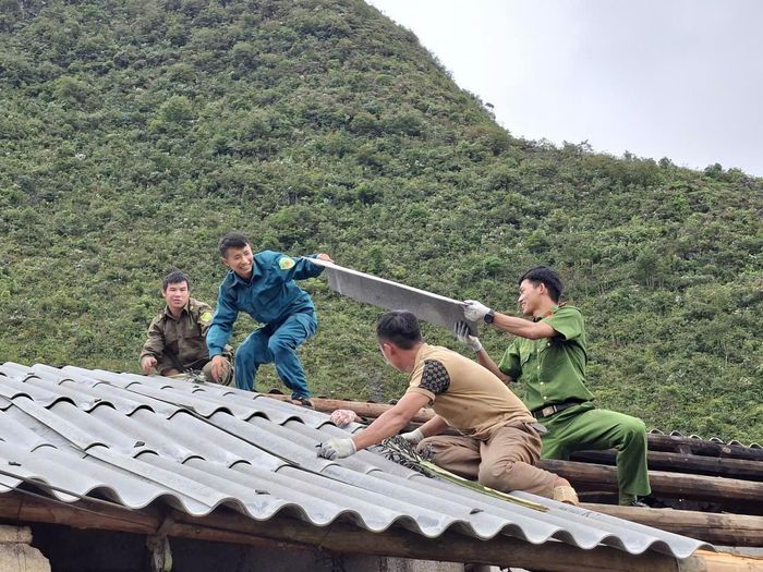Công an xã Lũng Phìn giúp gia đình ông Sùng Chúng Dế lợp lại mái nhà. (Ảnh:CATQ)