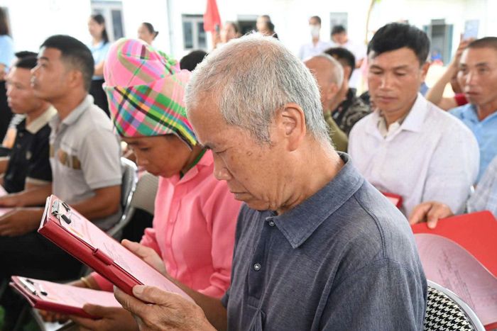 Người dân xúc động đọc giấy chứng nhận quyền sử dụng đất mới được nhận.