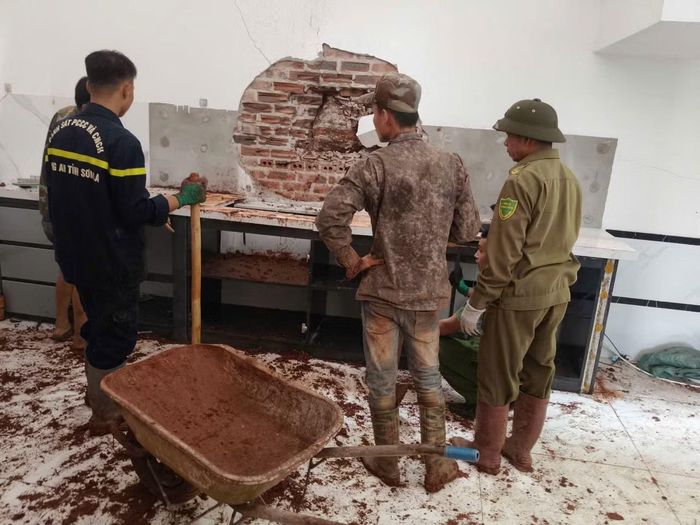 Cán bộ, chiến sĩ phối hợp lực lượng Công an xã và dân phòng hỗ trợ gia đình anh Lò Văn Hưng di chuyển tài sản, khắc phục hậu quả vụ sạt lở.