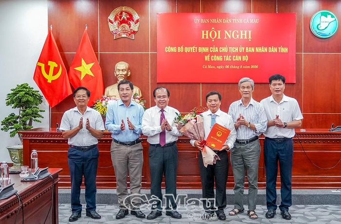 Phó Chủ tịch UBND tỉnh Nguyễn Minh Luân trao quyết định, tặng hoa đồng chí Huỳnh Ngọc Linh và chụp ảnh lưu niệm cùng