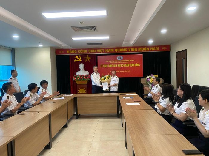 Đồng chí Phạm Văn Học - Bí thư Đảng ủy bộ phận, Kiểm toán trưởng KTNN chuyên ngành Ia trao Quyết định và tặng hoa chúc mừng đồng chí Đoàn Thanh Long được nhận Huy hiệu 30 năm tuổi Đảng. Ảnh: CTV