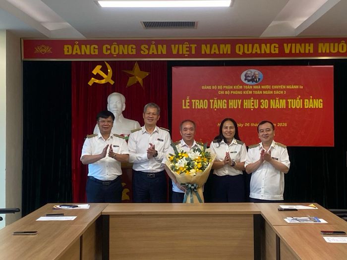 Lãnh đạo Đảng ủy bộ phận KTNN chuyên ngành Ia và các đại biểu tặng hoa chúc mừng đảng viên Đoàn Thanh Long được trao Huy hiệu 30 năm tuổi Đảng. Ảnh: CTV
