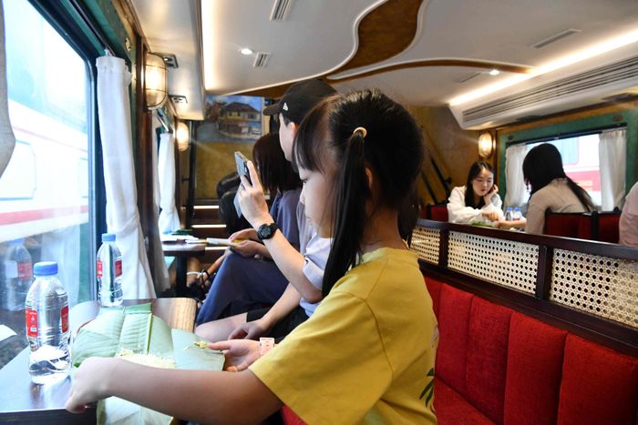 Không chỉ vậy, hành khách trên tàu lại được chiêu đãi bằng những bữa tiệc văn hóa khác - món ăn nhẹ phục vụ là xôi nếp, bánh rán, đặc biệt là món cốm mang đậm hương sắc Thủ đô. Trong ảnh, một du khách nhí đang háo hức thưởng thưởng món xôi cốm… 