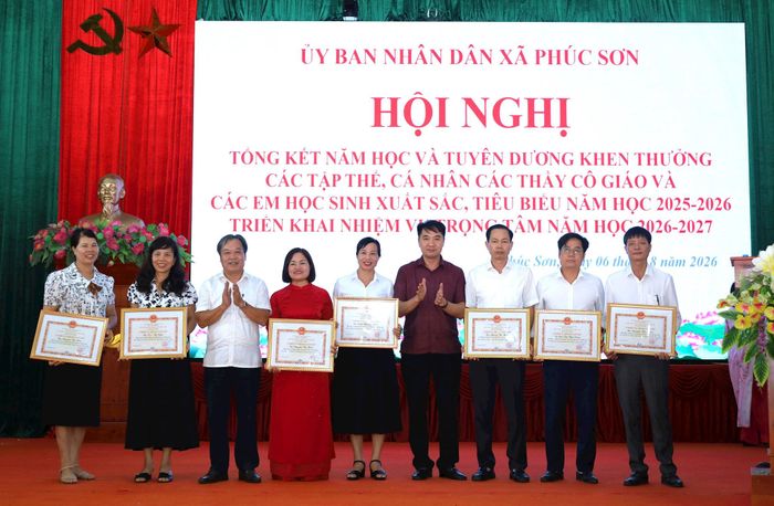 Phó Bí thư Thường trực Đảng ủy xã Phúc Sơn Trần Việt Thắng và Phó Chủ tịch HĐND xã Phúc Sơn Vũ Văn Chuyên khen thưởng giáo viên đạt danh hiệu "Chiến sĩ thi đua cơ sở". Ảnh: Kim Nhuệ