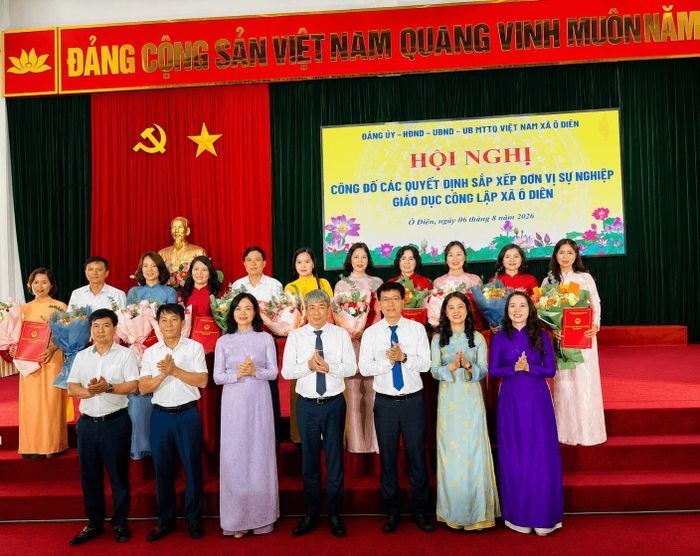 Lãnh đạo xã Ô Diên trao quyết định và tặng hoa chúc mừng cán bộ quản lý các đơn vị sự nghiệp giáo dục sau sắp xếp. Ảnh: Ánh Bình