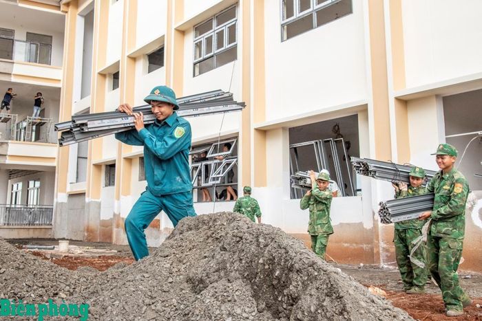 Bộ đội Biên phòng và dân quân địa phương hỗ trợ vận chuyển cửa để lắp ráp tại khu nhà hành chính.Ảnh: Lê Văn Chương