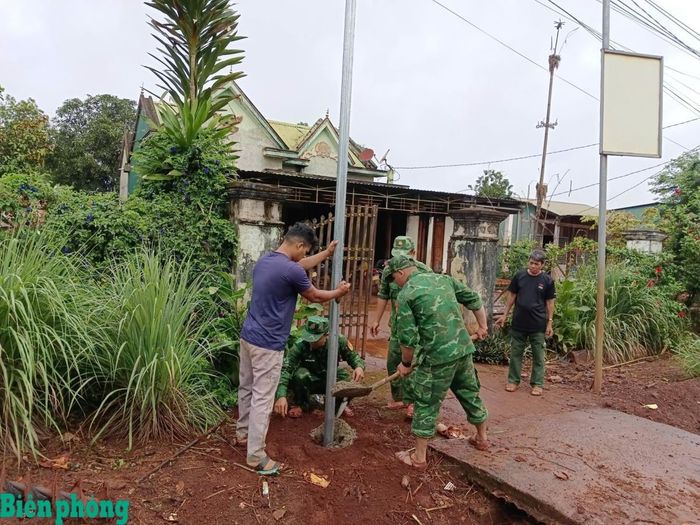 Cán bộ, chiến sĩ Đồn Biên phòng cửa khẩu quốc tế Lệ Thanh và các lực lượng lắp đặt trụ đèn năng lượng mặt trời tại thôn Mook Trêl, xã Ia Dom, tỉnh Gia Lai. Ảnh: Thanh Bình