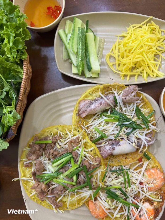 Miếng bánh giòn rụm, vị ngọt của tôm hay mực, độ mềm của thịt bò, vị chua nhẹ của xoài và hương thơm của rau sống hòa quyện tạo nên một tổng thể hài hòa, khiến thực khách ăn mãi mà không thấy ngán. (Nguồn: Vietnam+)