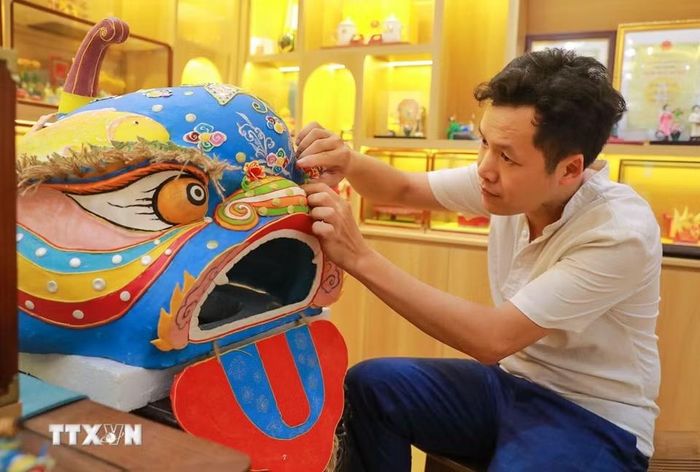 Nghệ nhân Đặng Văn Hậu thực hiện tác phẩm tò he Đầu sư tử truyền thống nặng hơn 10kg. (Ảnh: Khánh Hòa/TTXVN)