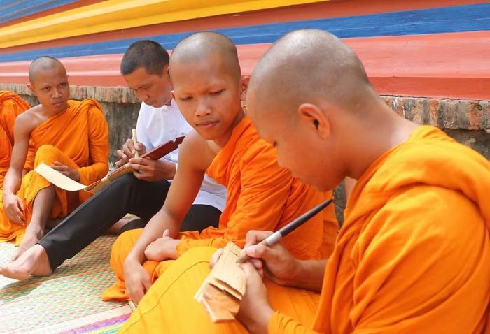 Người viết chữ trên lá buông, phải dùng một loại bút đặc biệt được làm bằng gỗ, vừa tay cầm, một đầu có mũi nhọn bằng kim loại gọi là Đek-cha để “khắc” chữ lên lá buông. (Ảnh: Công Mạo/TTXVN)
