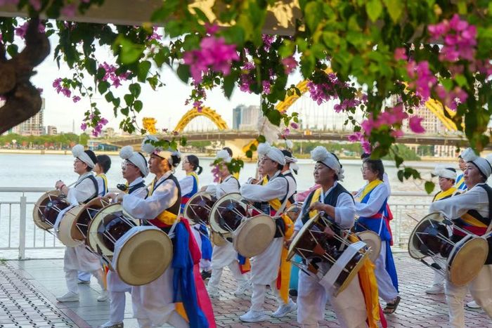 Đoàn diễu hành rực rỡ sắc màu với các nghệ sĩ biểu diễn nhạc cụ truyền thống Hàn Quốc nổi bật dưới vòm hoa giấy bên bờ sông Hàn. (Ảnh: Thanh Phong/Vietnam+)