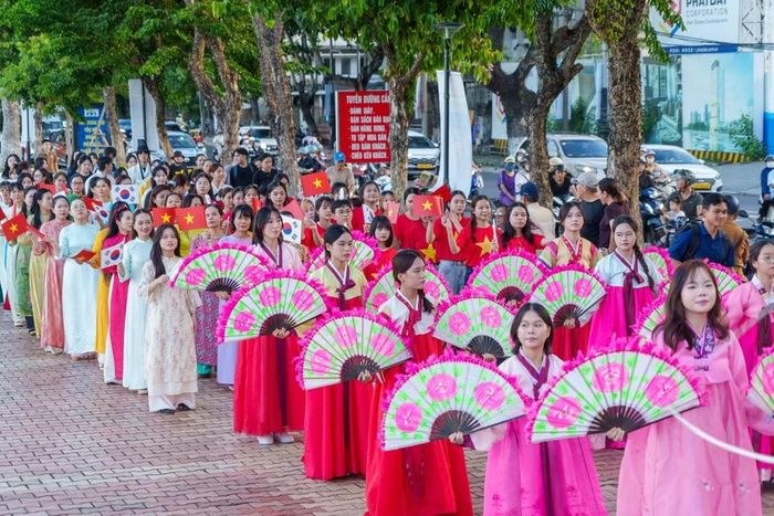 Ngay sau đoàn múa quạt là đoàn diễu hành mặc Áo dài Việt Nam cầm cờ hai nước vẫy chào, thể hiện tình hữu nghị bền chặt. (Ảnh: Thanh Phong/Vietnam+)