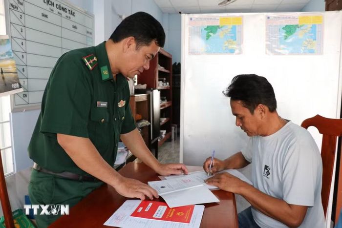 Thiếu tá Thạch Hưm Sâm Bô, cán bộ kiểm soát hành chính Tổ công tác Biên phòng Định An, xã Đại An hướng dẫn ngư dân khai báo khi tàu cập Cảng cá Định An. (Ảnh: Thanh Hòa/TTXVN)