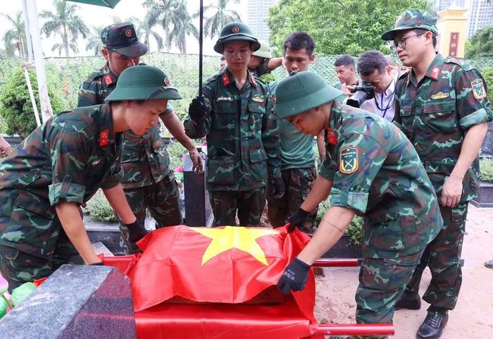Thực hiện nghi thức phủ Quốc kỳ trang trọng, tri ân Anh hùng liệt sỹ đã hy sinh vì độc lập, tự do của Tổ quốc tại Nghĩa trang Mai Dịch (phường Phú Diễn). (Ảnh: Văn Điệp/TTXVN)